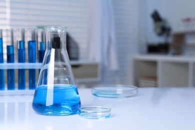 Photo of Laboratory analysis. Different glassware with blue liquid on white table indoors, space for text