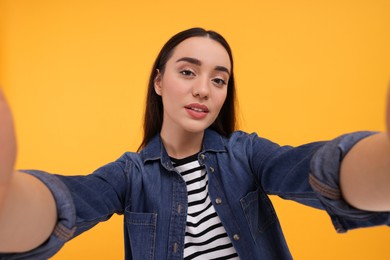 Photo of Young woman taking selfie on yellow background