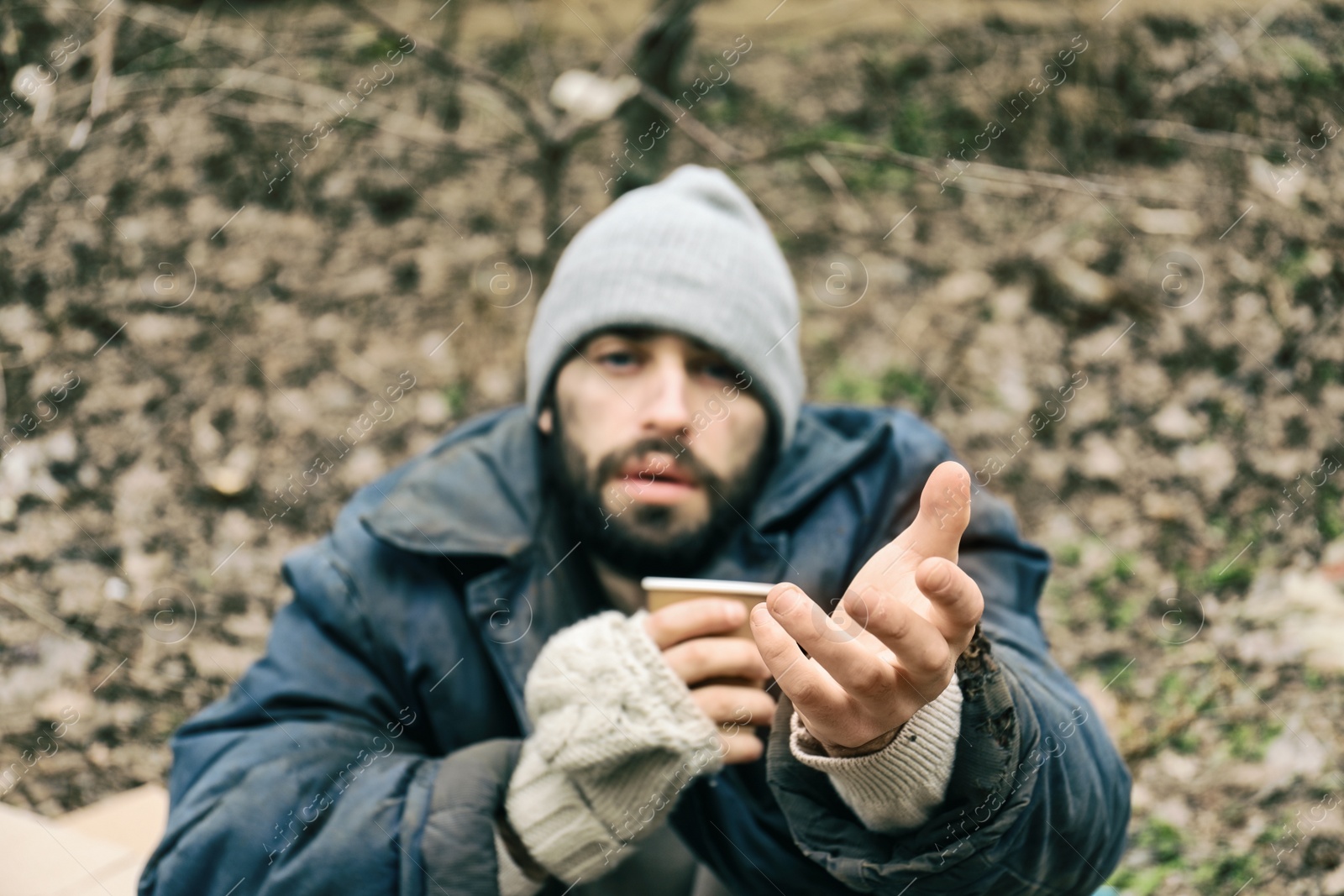 Photo of Poor homeless man with cup in city park