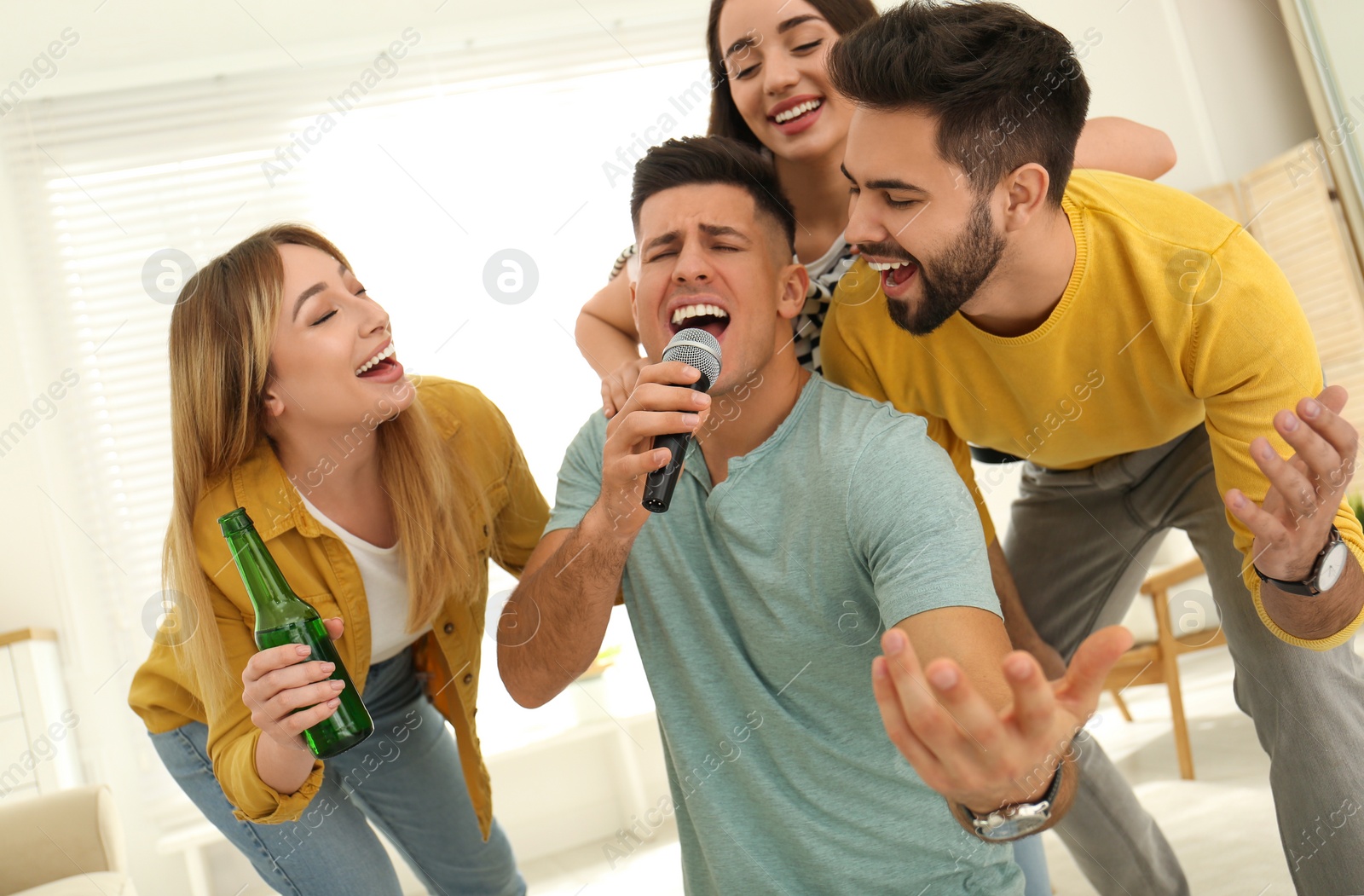 Photo of Happy friends singing karaoke together at home