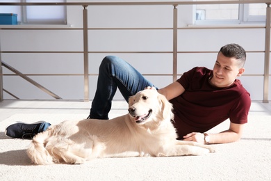 Photo of Handsome man with dog lying on carpet at home