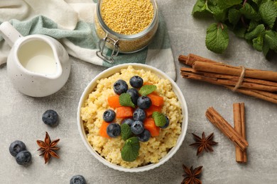 Tasty millet porridge with blueberries, pumpkin and mint in bowl on light grey table, flat lay