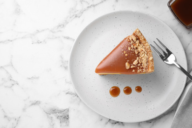 Piece of delicious cake with caramel served on white marble table, flat lay. Space for text