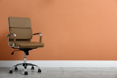 Modern office chair near orange coral wall indoors. Space for text