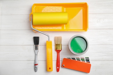 Flat lay composition with can of paint, brushes and renovation tools on white wooden background