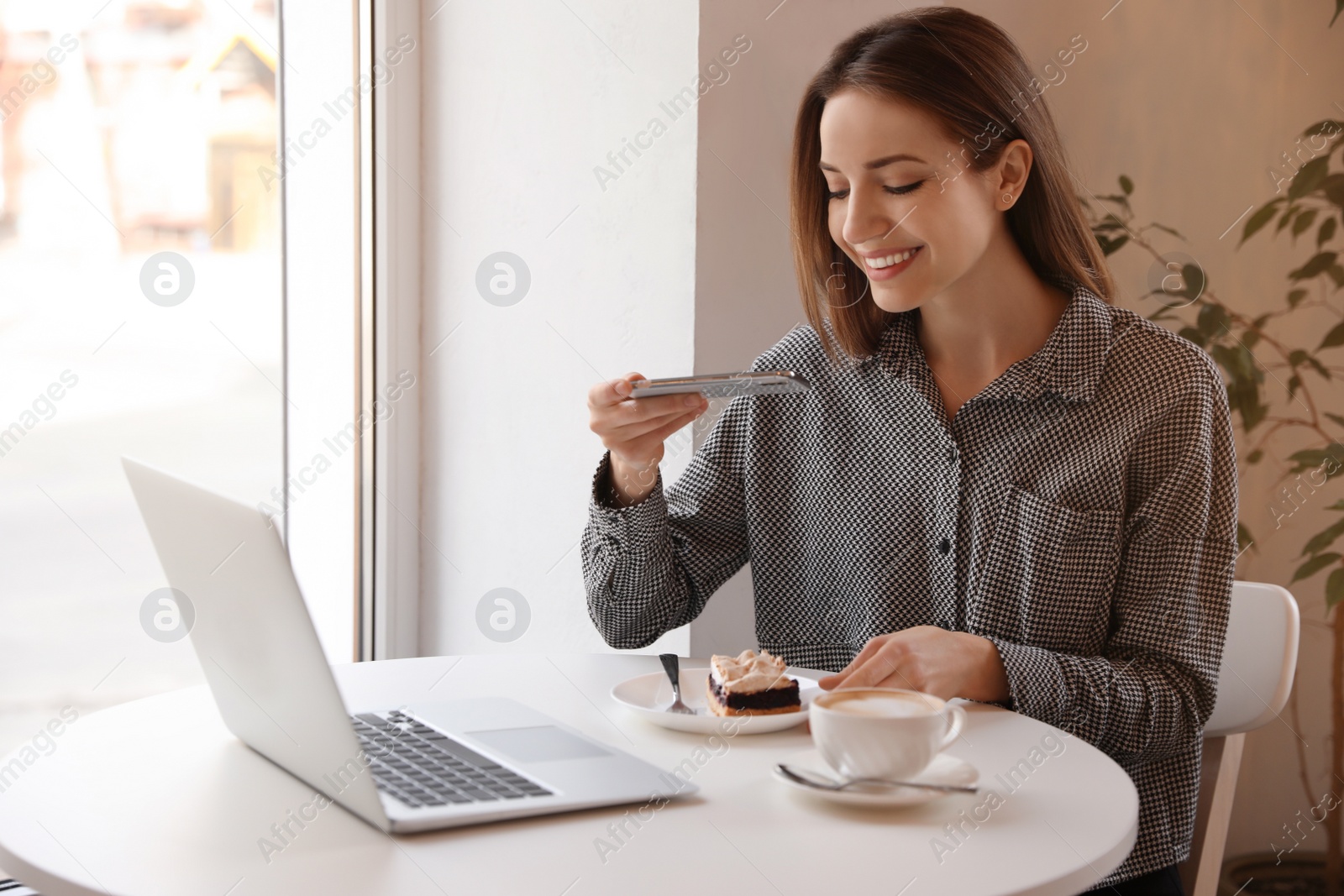 Photo of Young blogger taking photo of dessert in cafe