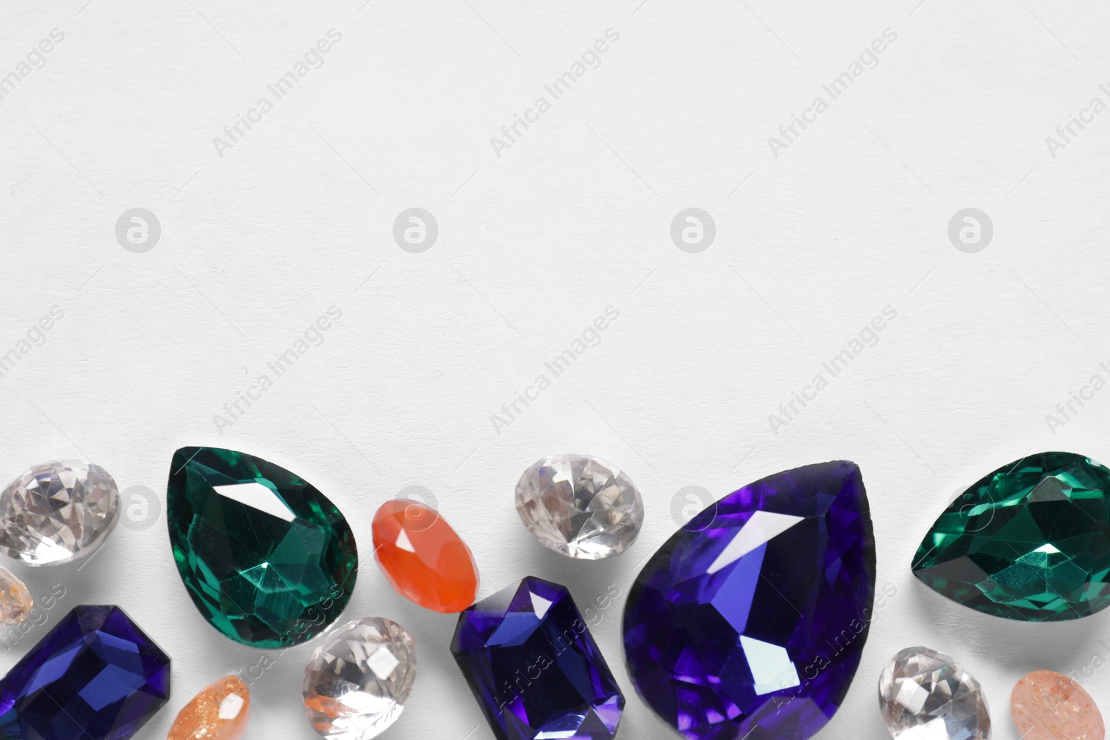 Photo of Different beautiful gemstones for jewelry on white background, top view. Space for text