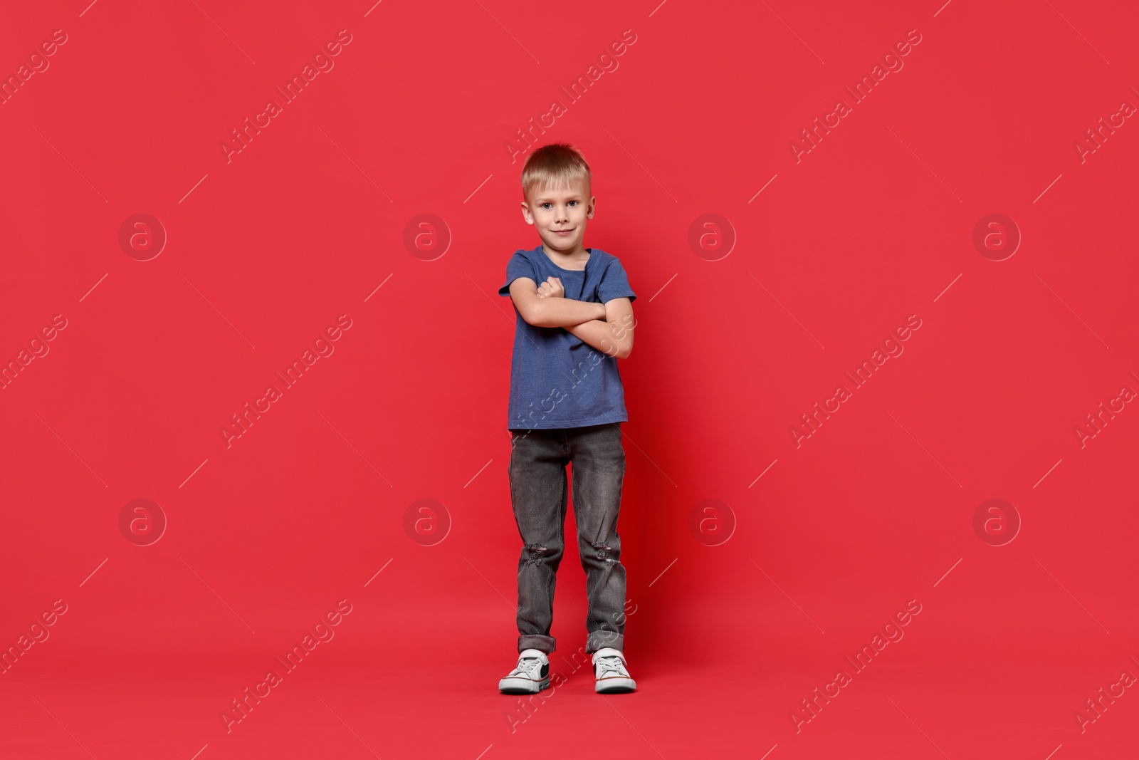 Photo of Happy little boy dancing on red background