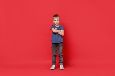 Photo of Happy little boy dancing on red background