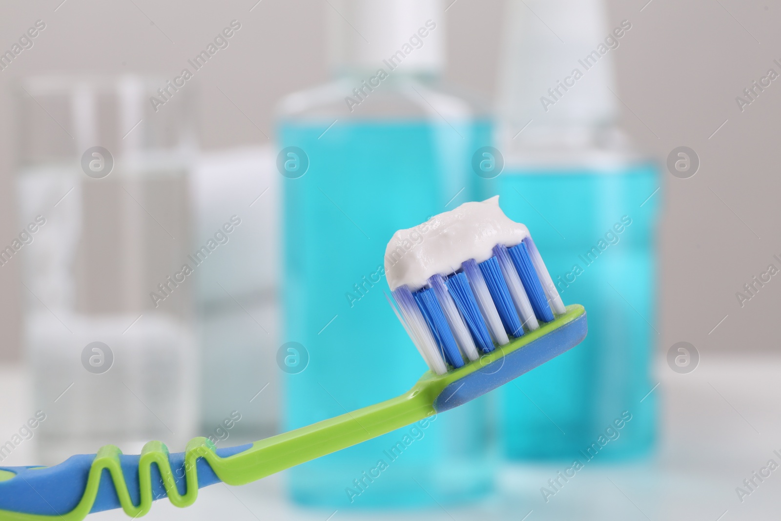 Photo of Toothbrush with paste near mouthwash on blurred background, closeup