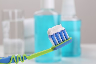 Photo of Toothbrush with paste near mouthwash on blurred background, closeup