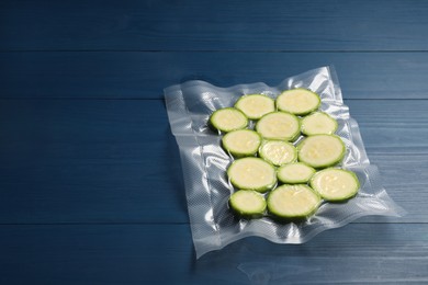 Photo of Plastic bag with cut zucchinis on blue wooden table. Space for text