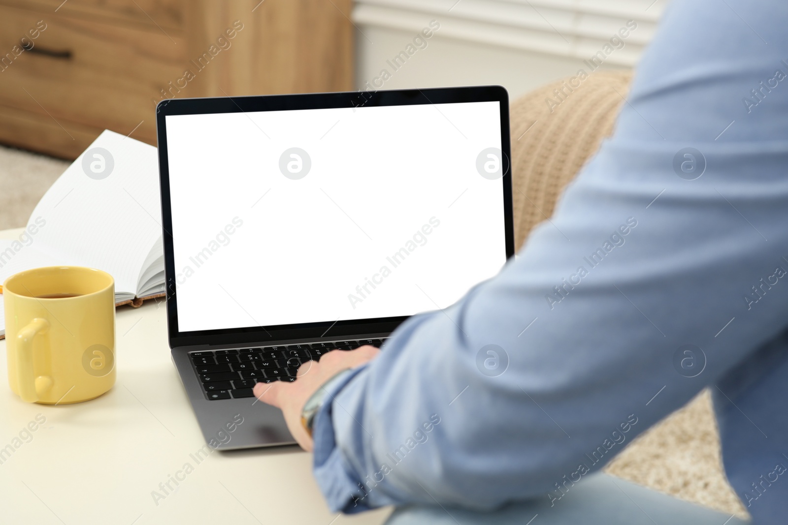 Photo of Man working with laptop at white table indoors, closeup
