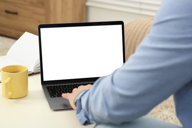 Man working with laptop at white table indoors, closeup