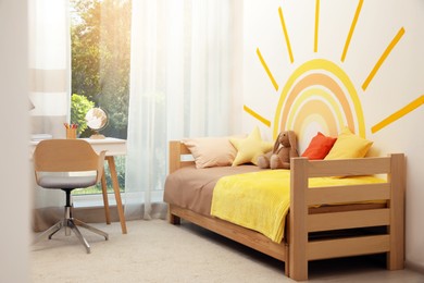 Cute child's room interior with beautiful sun painted on wall