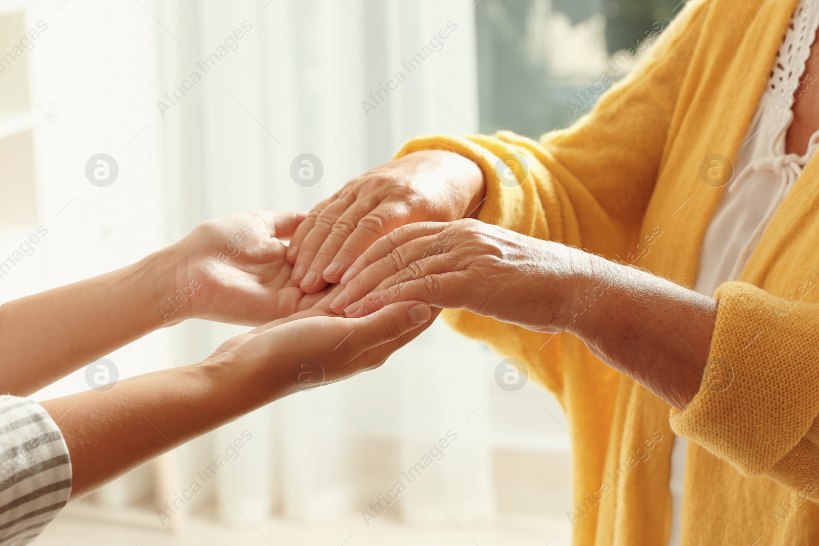 Photo of Helping hands on blurred background, closeup. Elderly care concept