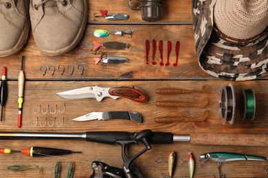Flat lay composition with fishing equipment on wooden background