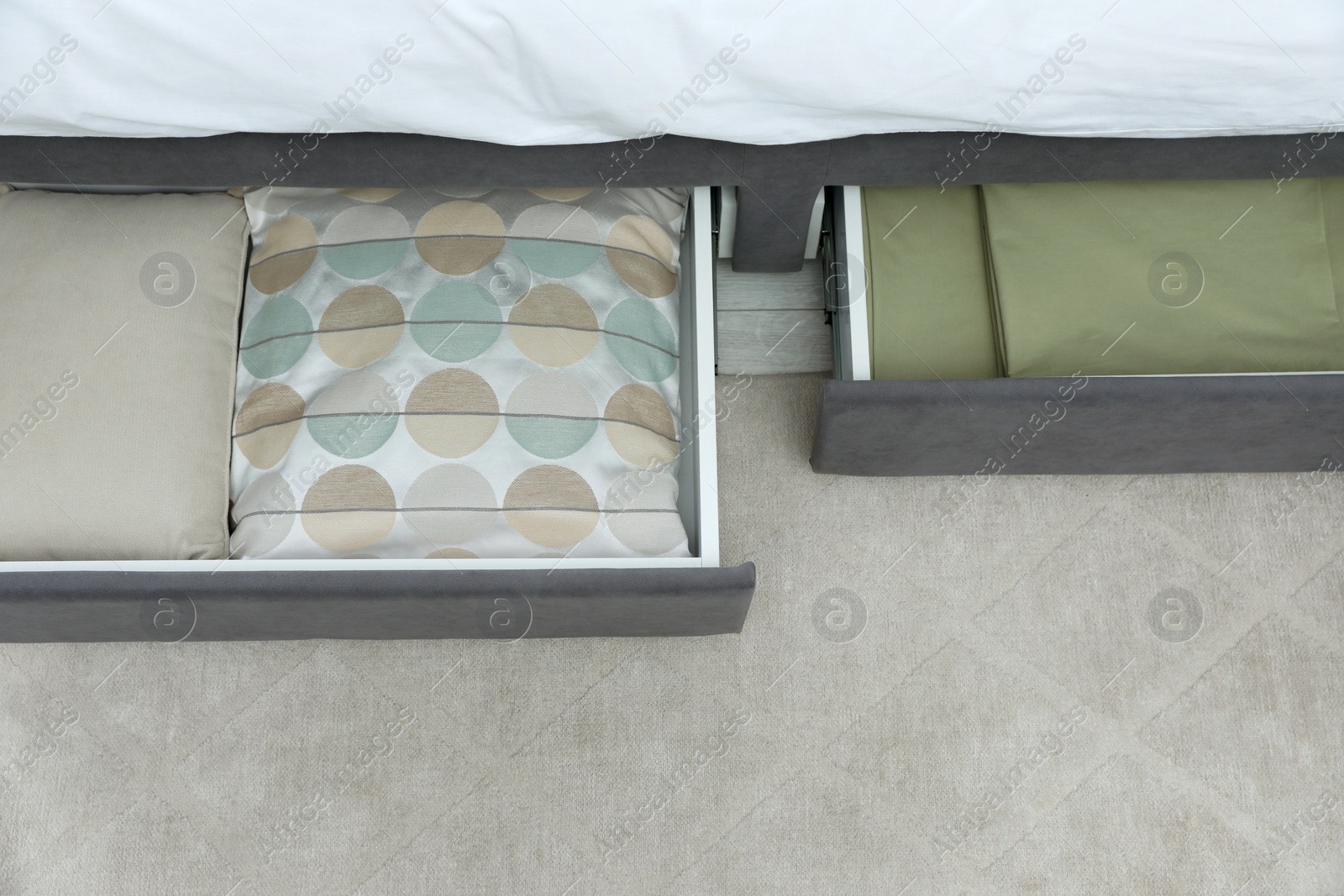 Photo of Storage drawers with bedding under modern bed in room, above view