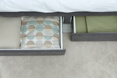 Storage drawers with bedding under modern bed in room, above view