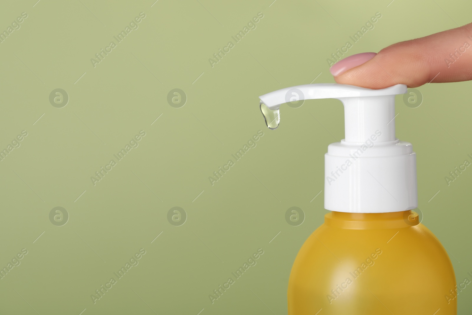 Photo of Woman using cleansing gel on pale olive background, closeup. Space for text