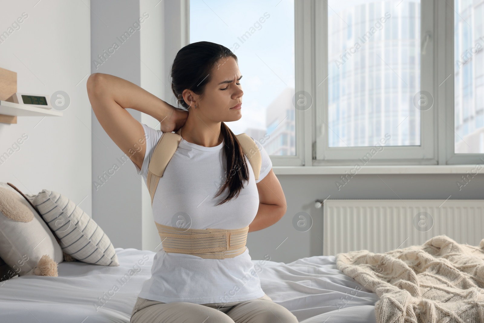 Photo of Woman with orthopedic corset sitting in bedroom