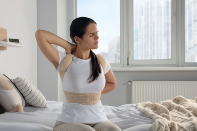 Woman with orthopedic corset sitting in bedroom