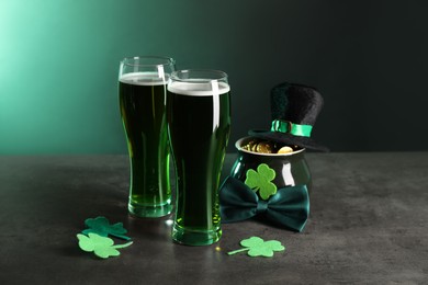 Photo of St. Patrick's day celebration. Green beer, leprechaun hat, pot of gold and decorative clover leaves on grey table