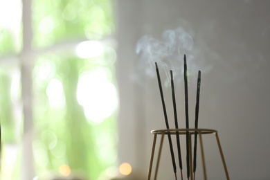 Photo of Incense sticks smoldering on blurred background, closeup. Space for text