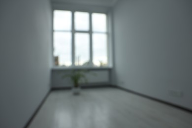 Photo of Blurred view of empty office room with windows and potted houseplants