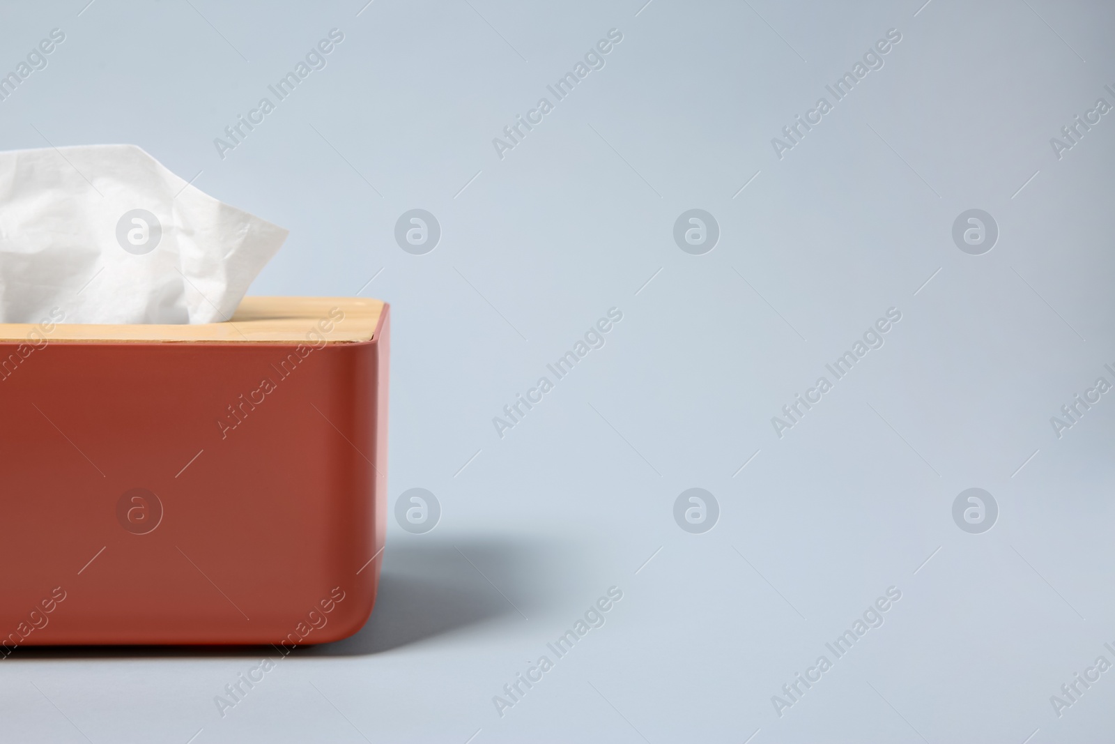 Photo of Holder with paper tissues on light grey background, closeup. Space for text