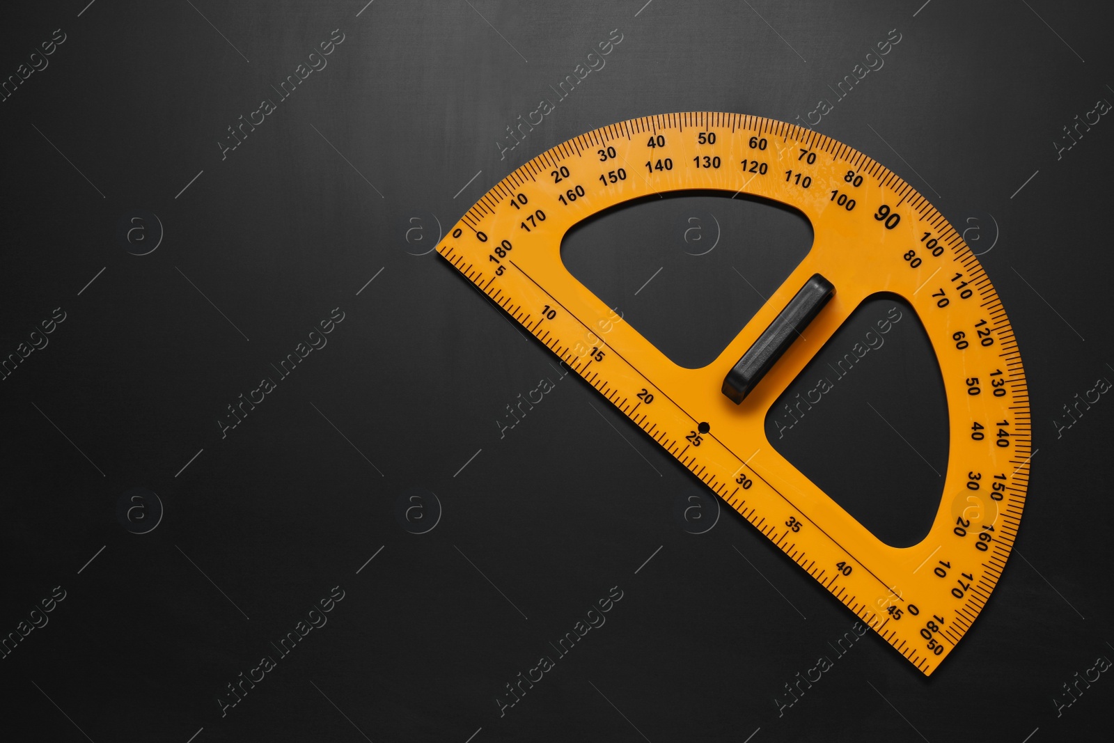 Photo of Yellow protractor on blackboard, top view. Space for text