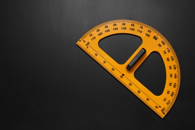 Photo of Yellow protractor on blackboard, top view. Space for text