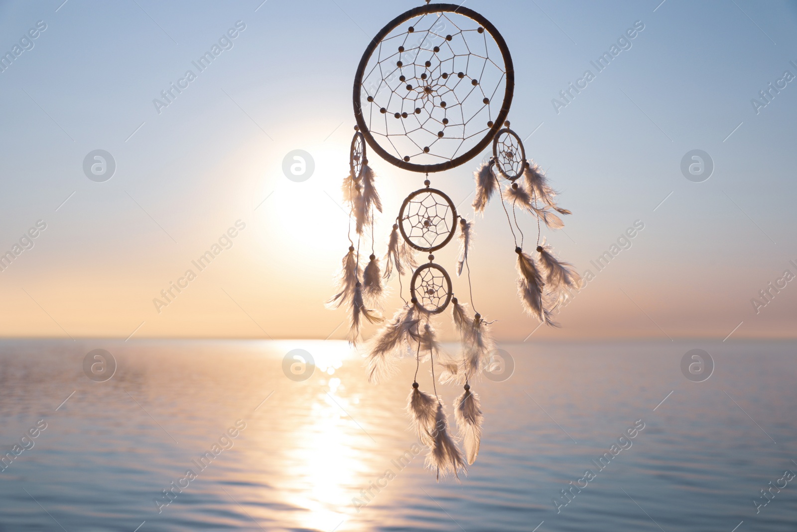 Photo of Beautiful handmade dream catcher near river at sunset. Space for text