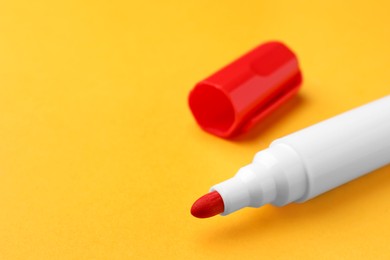 Photo of Bright red marker on orange background, closeup. Space for text