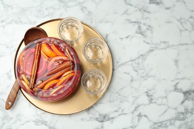 Photo of Wooden ladle, empty glasses near bowl of aromatic punch drink on white marble table, top view. Space for text