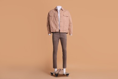 Photo of Male mannequin with sneakers dressed in white shirt, jacket and pants on beige background. Stylish outfit