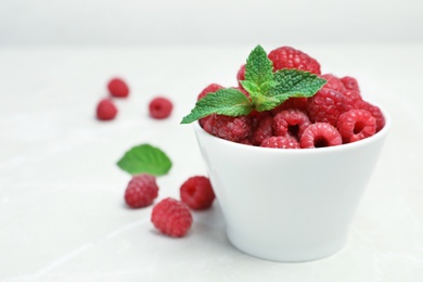 Bowl with ripe aromatic raspberries on table