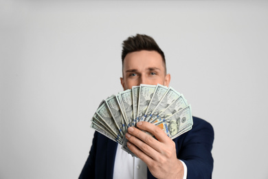 Photo of Happy man with cash money against light grey background, focus on hand