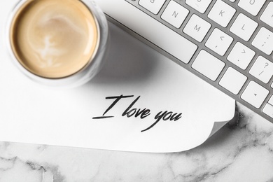 Photo of Card with text I Love You, cup of coffee and keyboard on white marble table, flat lay