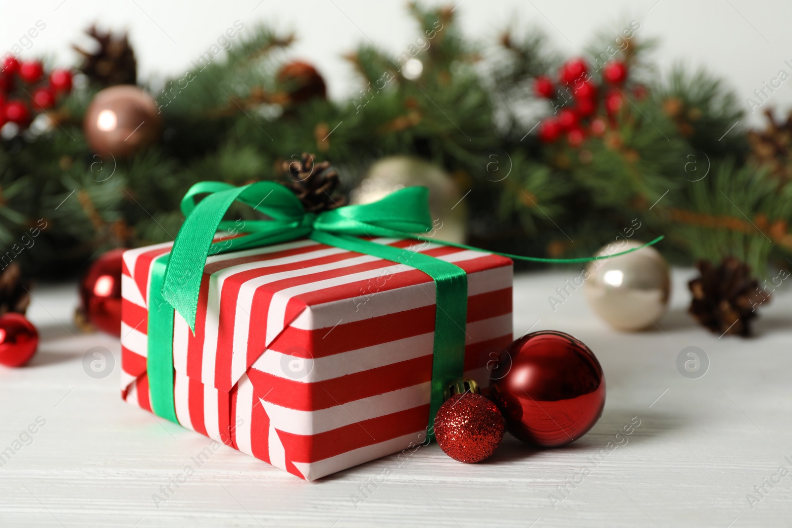 Photo of Gift box with green bow and Christmas balls on wooden table