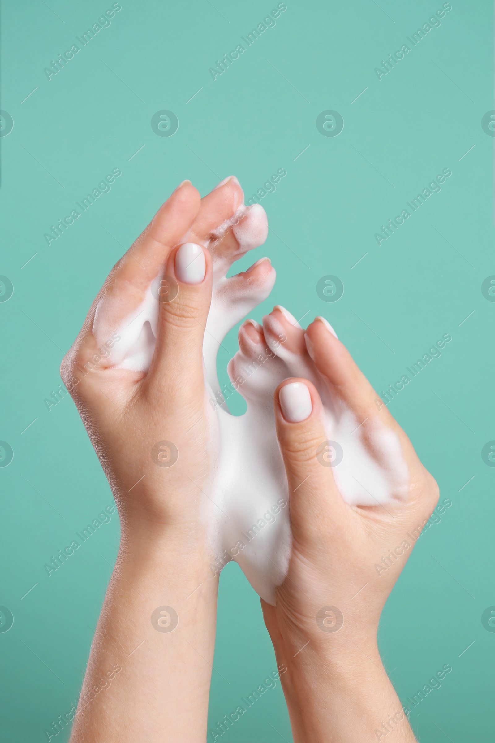 Photo of Woman washing hands with cleansing foam on green background, closeup. Skin care cosmetic