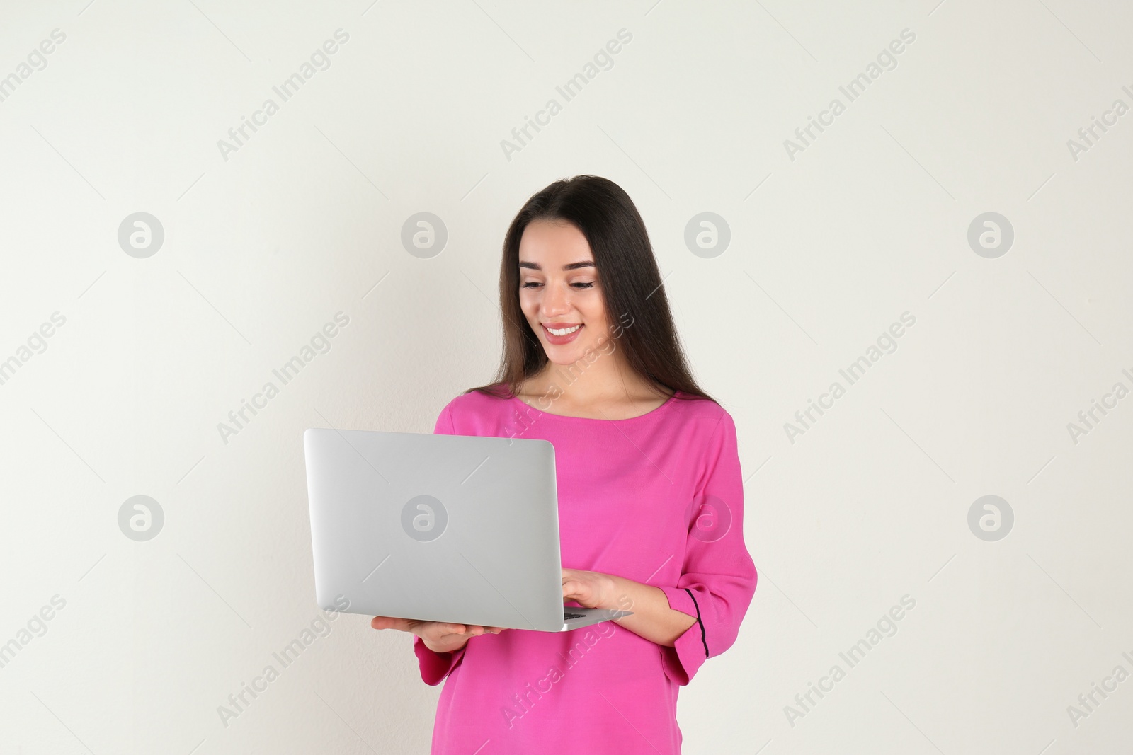 Photo of Portrait of young woman in casual outfit with laptop on light background