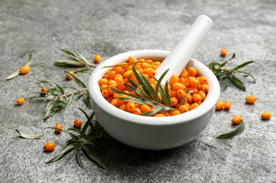 Photo of Fresh ripe sea buckthorn in mortar on grey table