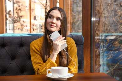 Woman listening to audiobook at table in cafe