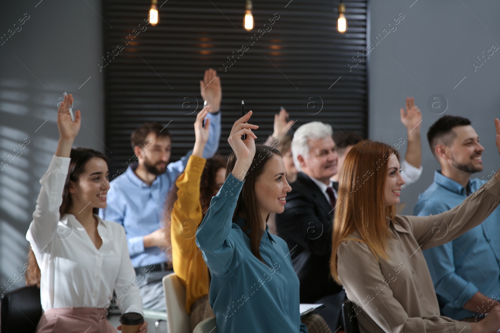 Photo of People raising hands to ask questions at seminar in office