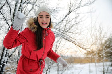 Young woman holding snowball outdoors on winter day. Space for text