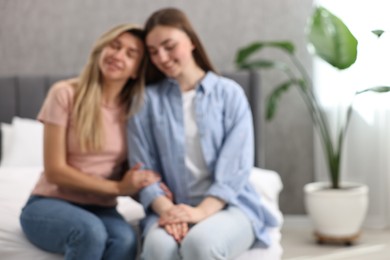 Photo of Blurred view of happy young women sitting on bed at home, space for text