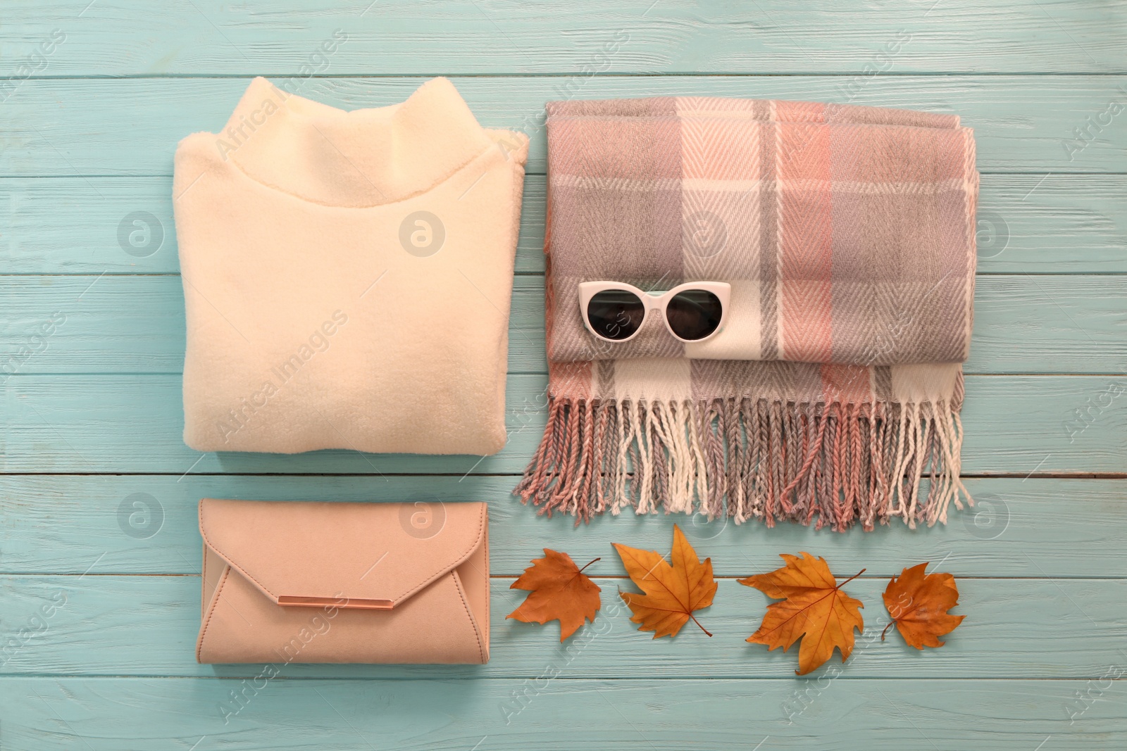 Photo of Flat lay composition with sweater and dry leaves on light blue wooden background. Autumn season