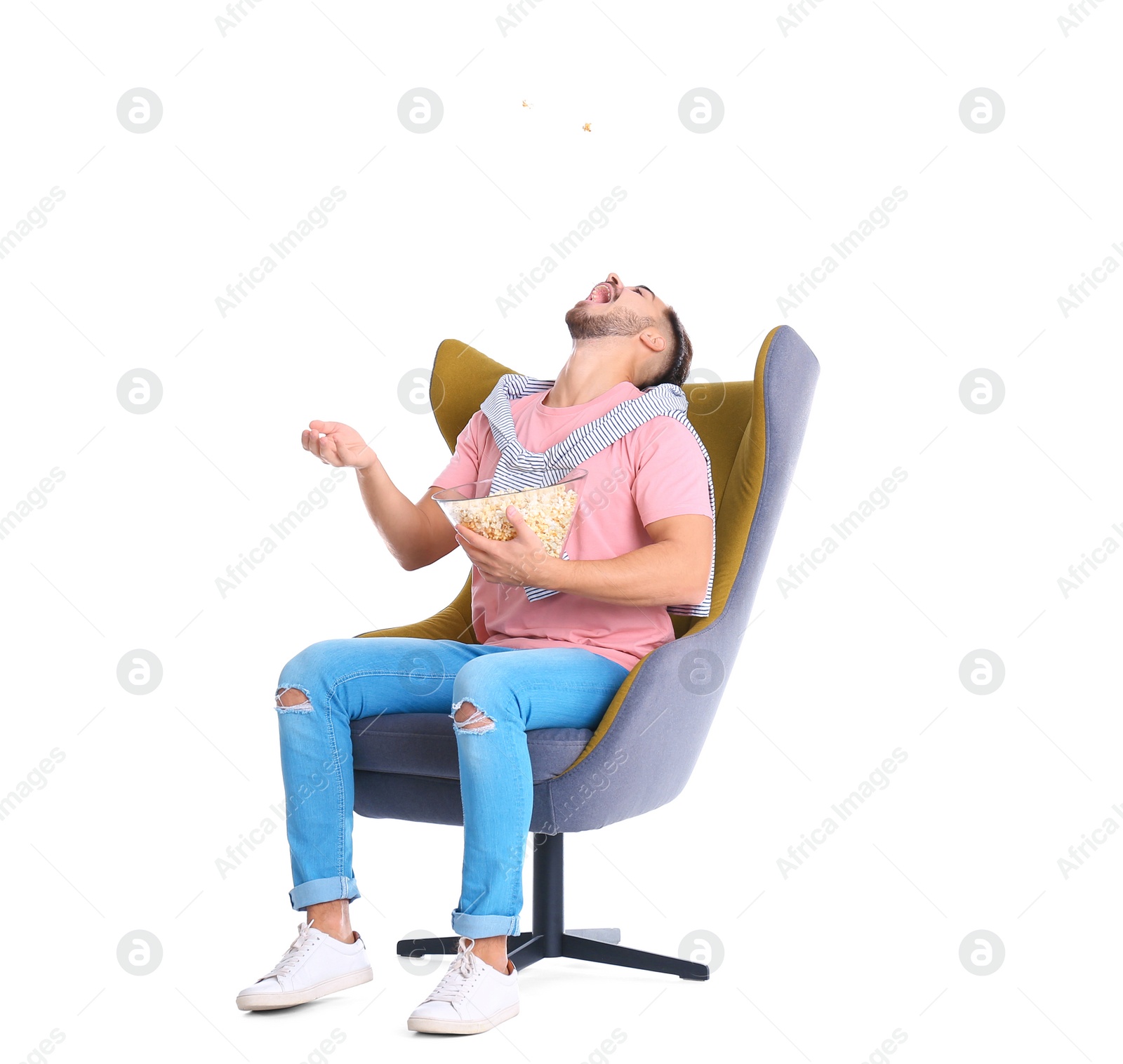 Photo of Handsome young man with bowl of popcorn in armchair on white background. Watching cinema