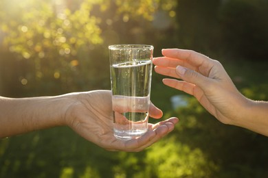 Man giving glass of fresh water to woman outdoors, closeup